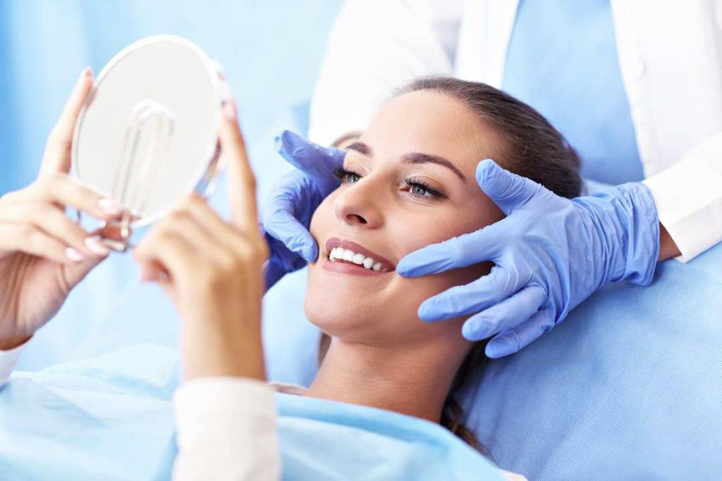Woman Visiting The Dentist Smiling Into A Mirror